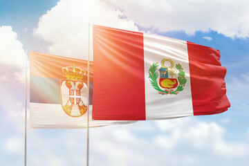 Sunny blue sky and flags of peru and serbia
