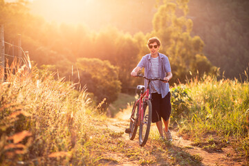 Young man wearing sunglasses riding a bicycle and having fun on a sunny afternoon. - Powered by Adobe