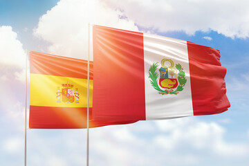 Sunny blue sky and flags of peru and spain