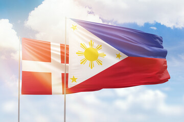 Sunny blue sky and flags of philippines and denmark