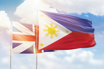 Sunny blue sky and flags of philippines and great britain