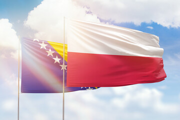 Sunny blue sky and flags of poland and bosnia