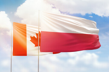 Sunny blue sky and flags of poland and canada