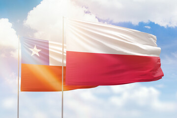 Sunny blue sky and flags of poland and chile