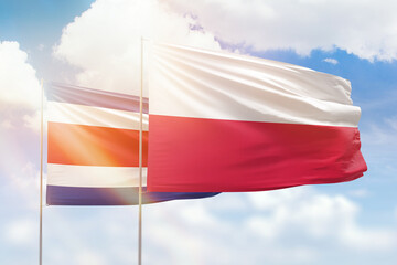Sunny blue sky and flags of poland and costa rica