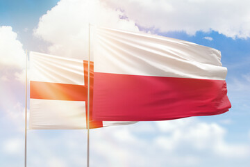Sunny blue sky and flags of poland and england