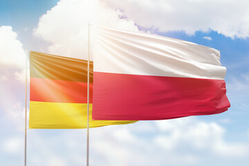 Sunny blue sky and flags of poland and germany