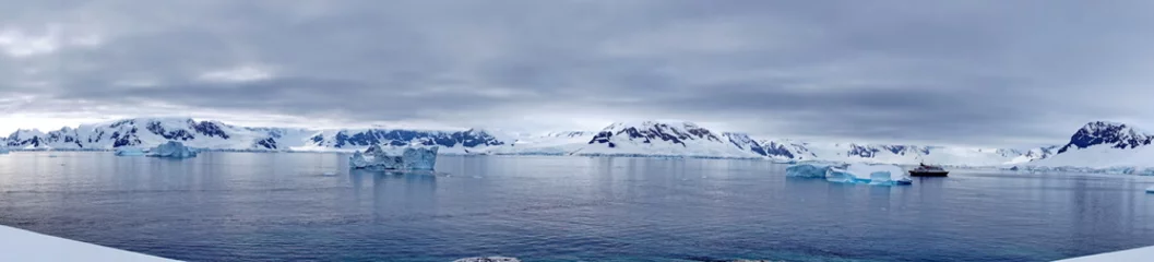 Panorama von Eisbergen, die in der Bucht schwimmen, vor schneebedeckten Bergen am Portal Point in der Antarktis © Angela