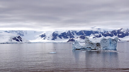 Iceberg floating in the bay in front of snow covered mountains at Portal Point in Antarctica