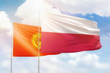 Sunny blue sky and flags of poland and kyrgyzstan