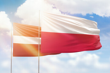 Sunny blue sky and flags of poland and latvia