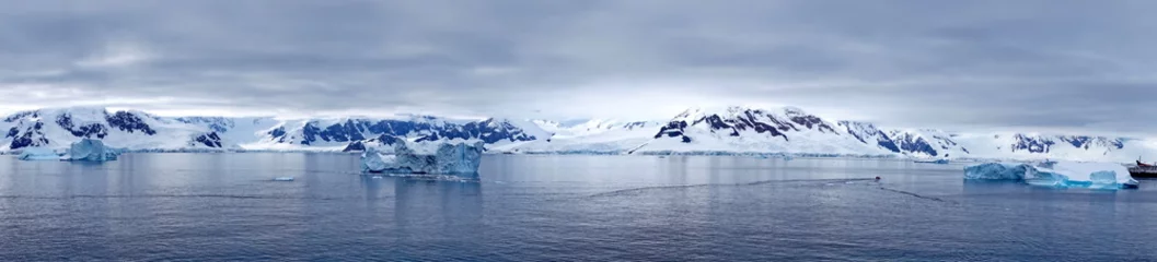 Panorama of icebergs floating in the bay, in front of snow covered moutains at Portal Point in Antarctica © Angela