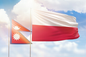 Sunny blue sky and flags of poland and nepal