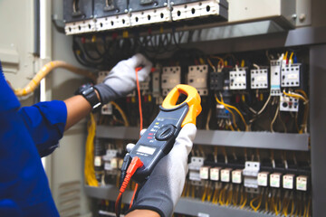 Electricity and electrical maintenance service, Engineer hand holding AC voltmeter checking electric current voltage at circuit breaker terminal and cable wiring main power distribution board.