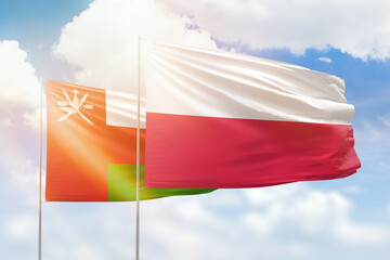 Sunny blue sky and flags of poland and oman