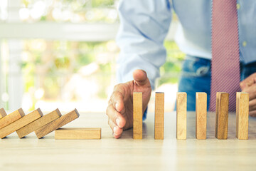 Close-up hand prevent wooden block not falling domino concepts of financial risk management and...