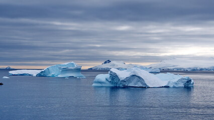 Icebergs floating in the bay in front of snow covered mountains at Portal Point in Antarctica