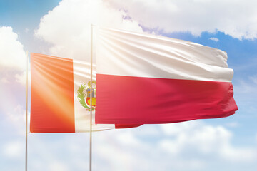 Sunny blue sky and flags of poland and peru