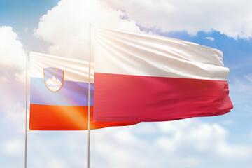 Sunny blue sky and flags of poland and slovenia