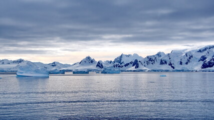 Fototapeta na wymiar Icebergs floating in the bay in front of snow covered mountains at Portal Point in Antarctica