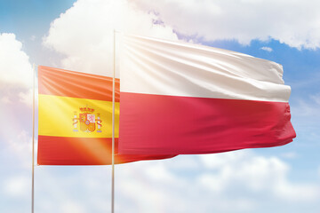 Sunny blue sky and flags of poland and spain