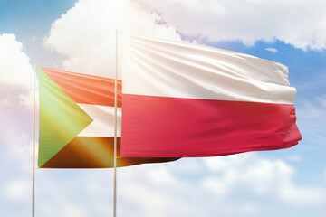 Sunny blue sky and flags of poland and sudan