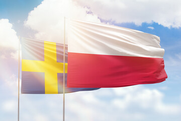 Sunny blue sky and flags of poland and sweden