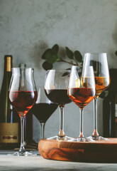 Wine glasses and bottles assortment. Red, white, rose wines on gray table background. Wine bar,...