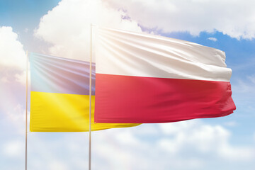 Sunny blue sky and flags of poland and ukraine