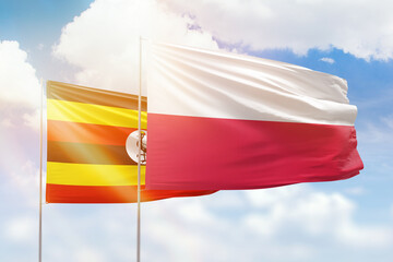 Sunny blue sky and flags of poland and uganda