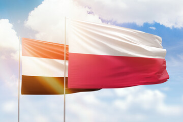 Sunny blue sky and flags of poland and yemen