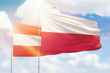 Sunny blue sky and flags of poland and austria