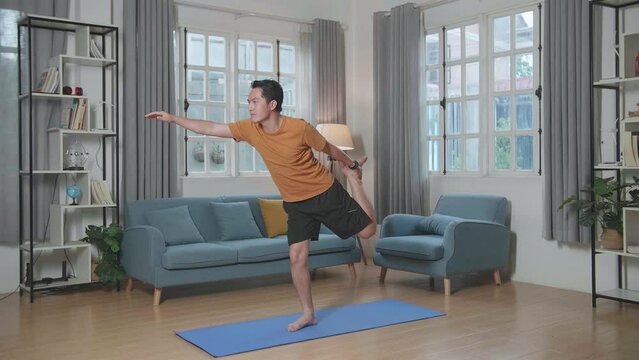 Asian Man Can'T Do Yoga In Law Lord Of The Dance Pose On Mat At Home

