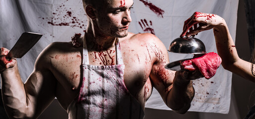 Shirtless butcher with wearing bloody apron posing with fresh raw meat.