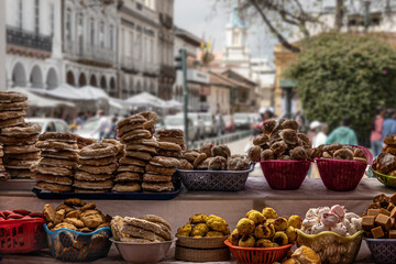 Traditional sweets: cookies, jelly, candy, chocolate and more at open market during catholic Corpus Christi celebration in Ecuador. Central square of Cuenca at background. Selective focus.