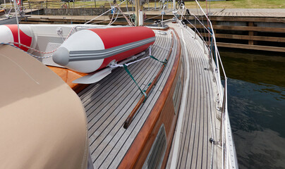 An elegant two masted sailboat (ketch) moored to a pier in a yacht marina. Wooden teak deck,...