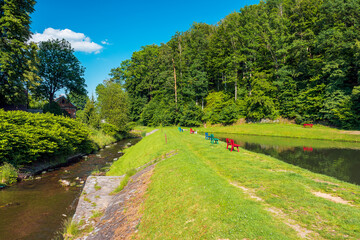 Colorful benches on the shore of the pond in Pokrzywna. The Złoty Potok river. A beautiful sunny day