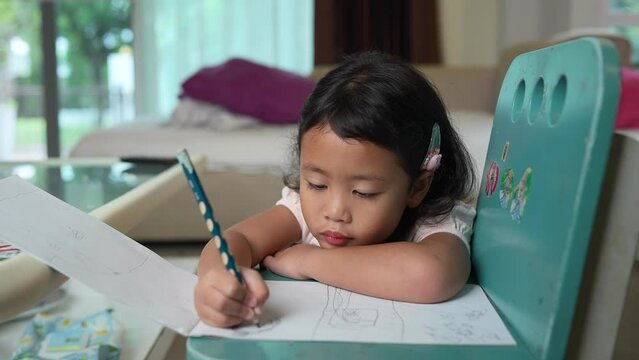 Small Child Drawing Picture On Blue Chair Indoor At Home.