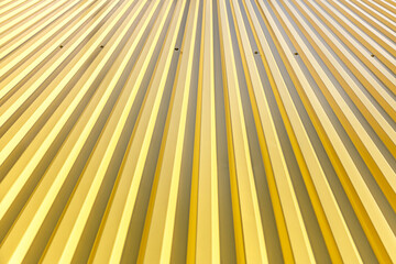 Fototapeta premium shining texture of yellow corrugated metal roof. modern industrial background.