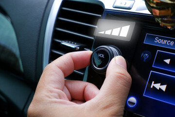 Driver hand adjust volume control on the car radio dashboard - obrazy, fototapety, plakaty