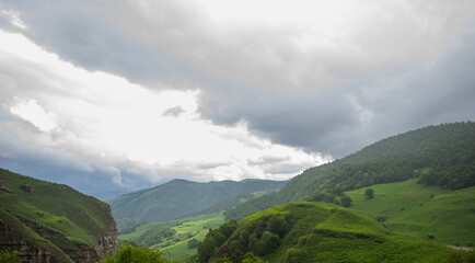 Beautiful spring landscape in the Caucasus Mountains with lush grassy hills and rocky slopes....