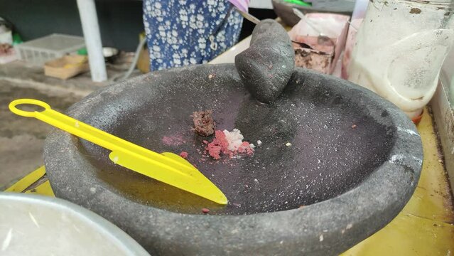 A merchant is mixing rujak spices. Rujak is a typical Indonesian food, consisting of fresh fruits and spicy spices.