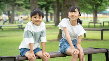 公園のベンチに座る小学生の男の子と女の子
