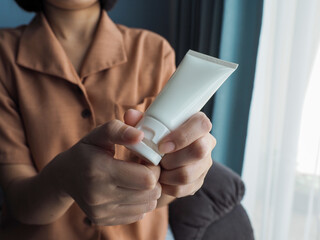 Woman holding a white cream tube on her hand. Skin care. Skin aging prevention. Beauty. Female confidence.