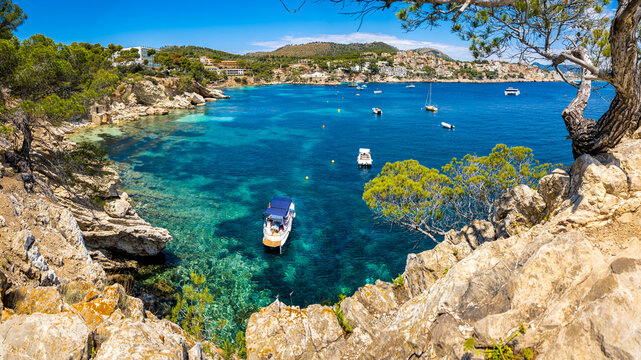 Panoramic view from headland Punta de na Cerdana over the bay of Cala Fornells with anchored boats to the bay Cal&oacute; de ses llisses with peninsula Punta de S'Estaca and apartment buildings behind.