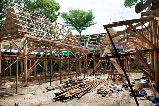 Thai professional carpenter people working and use teak build structure woodwork new building wooden church pavilion in construction site at Wat Sangkhatan temple in Bang Pai of Nonthaburi, Thailand