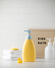 An empty bottle of baby soap and shampoo next to accessories in the bathroom. Template for design