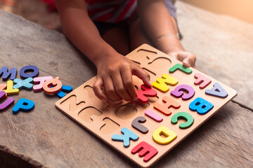 English alphabet made of square wooden. The child's hand grabs the English alphabet to put it in the correct block.