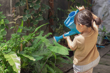 Portrait  image of 4-5 years old kid girl. Happy Asian child girl watering the green tree by water...