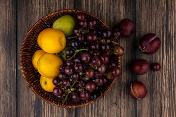 top view of fruits as grape pluot nectacots in basket and flavor king pluots on wooden background